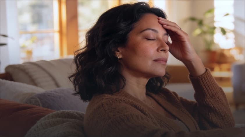 Woman resting on her couch with her eyes closed, worn out by fatigue