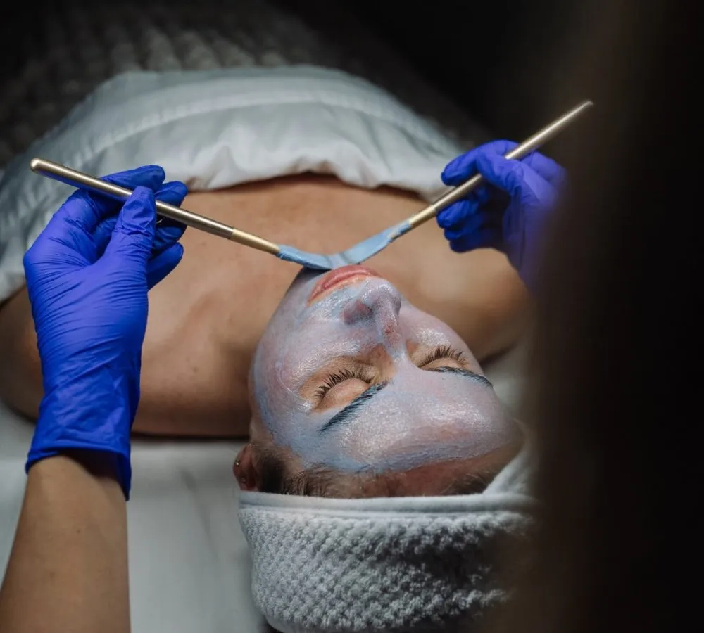 Clinician applying a facial treatment mask during a medical aesthetics visit